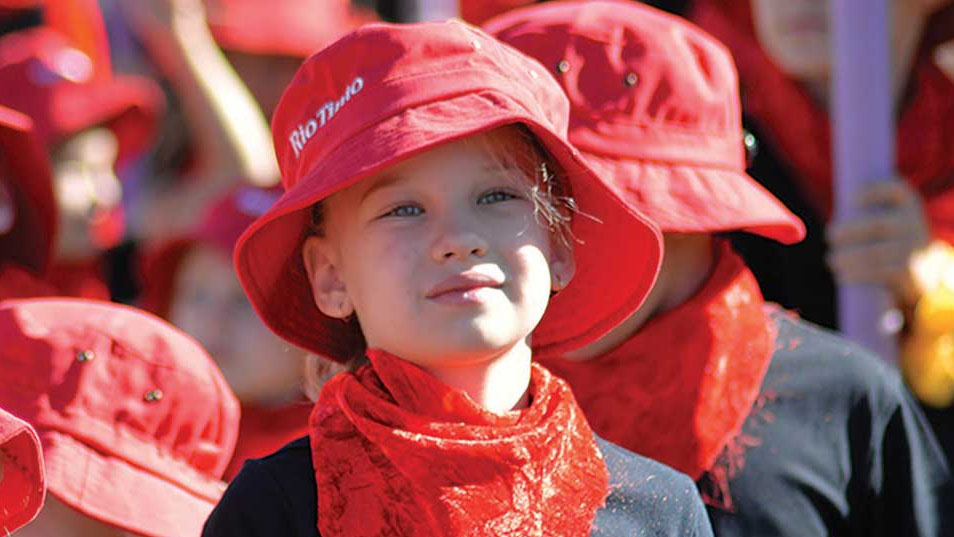 Child at Jarndunmunha Festival wearing a sponsor hat, outdoors