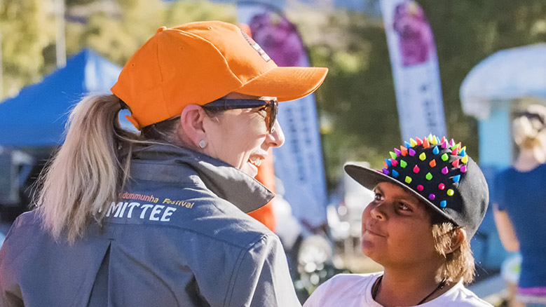 Volunteer smiling with a child at Jarndunmunha Festival, outdoors