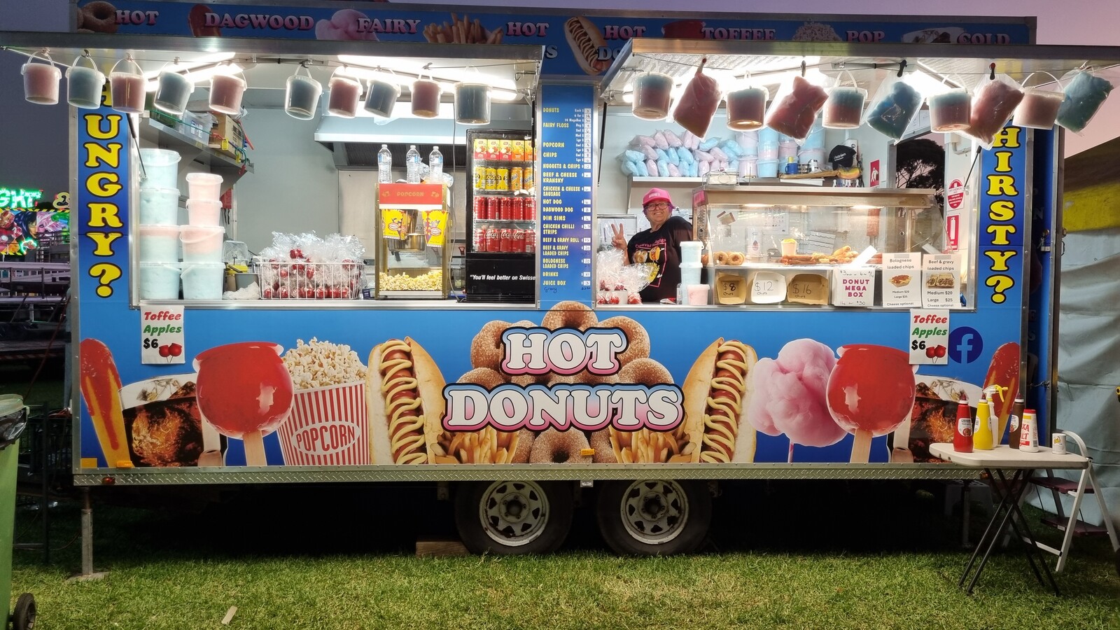 Carnival Delights food trailer at dusk with signage for hot donuts