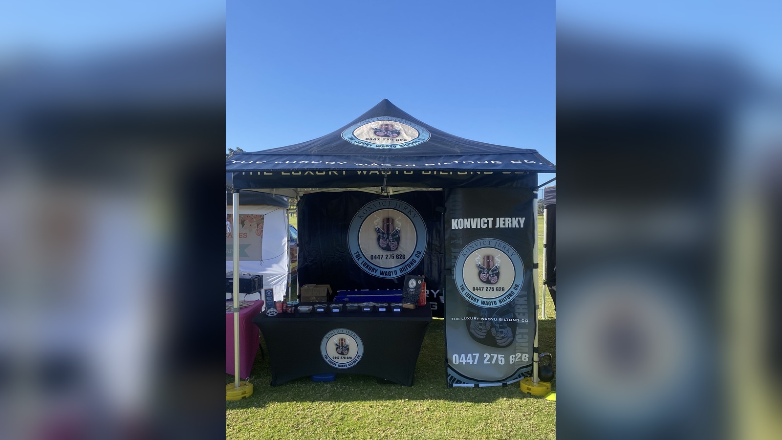 Konvict Jerky marquee with circular logo badges on all sides reading "The Luxury Wagyu Biltong Co." and a contact number