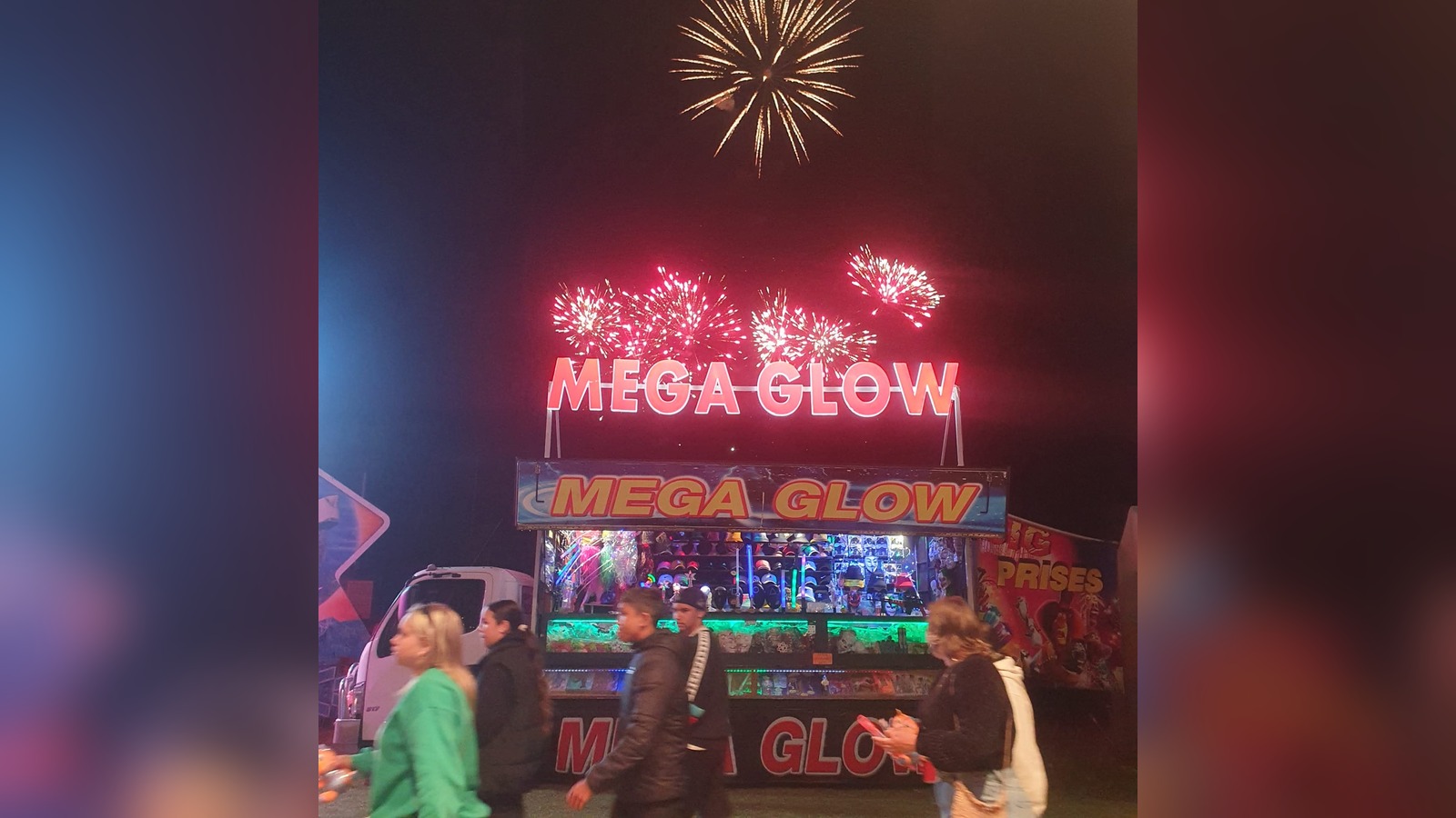 Mega Glow illuminated stall sign at night with fireworks overhead