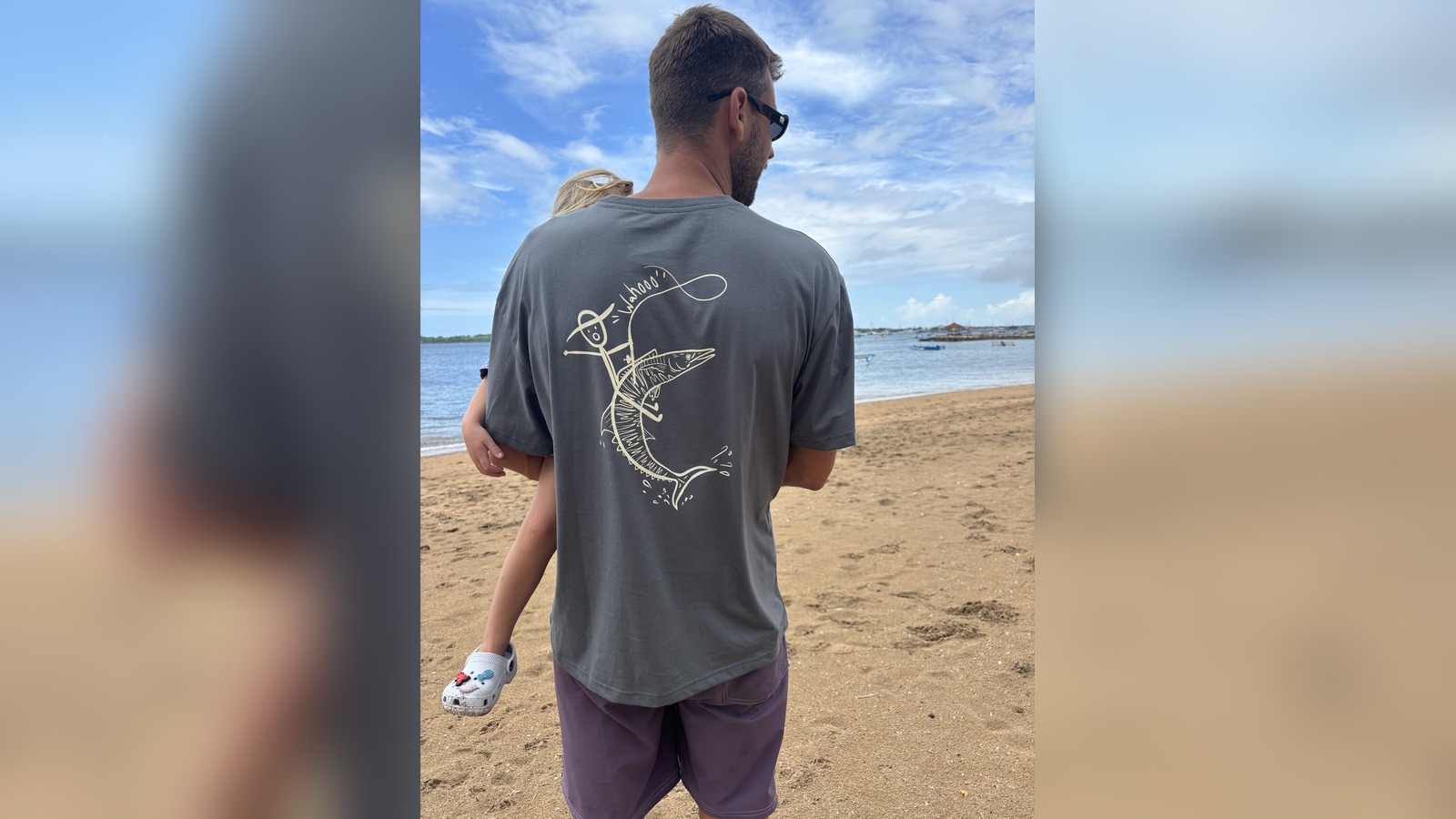 Man wearing a grey t-shirt printed with a hand-drawn "Wahoo" fish design