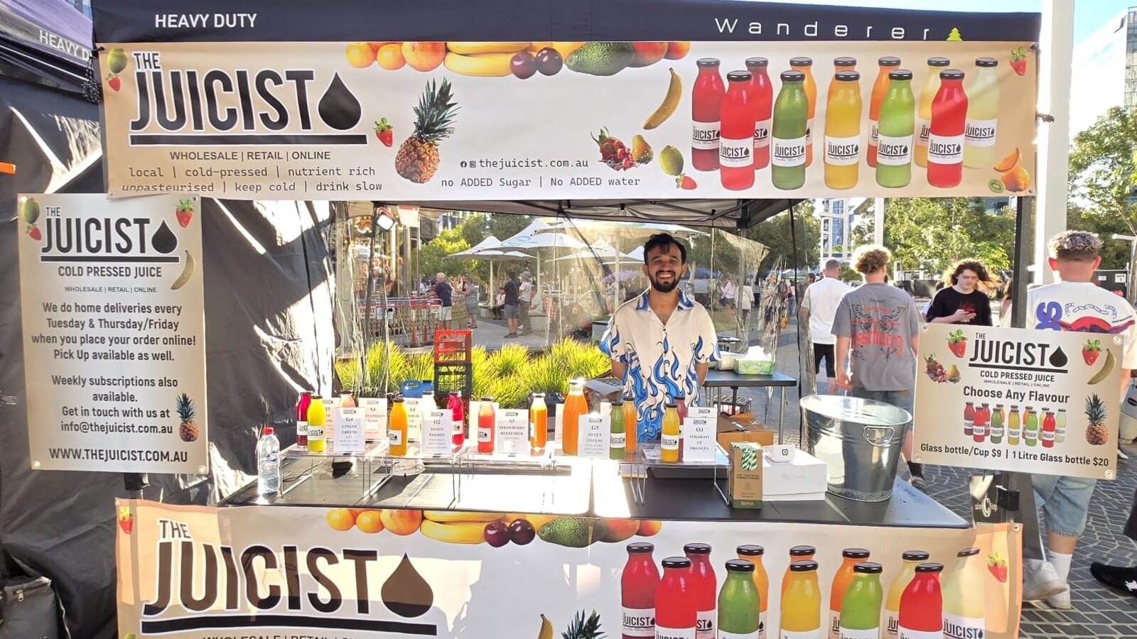 The Juicist cold-pressed juice stall with fruit-themed banners and rows of bottled juices