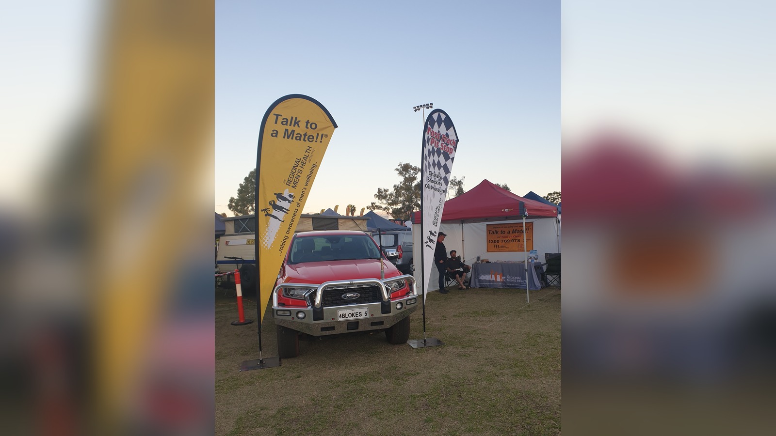 Talk to a Mate and Fast Track Pit Stop feather flags beside a red ute