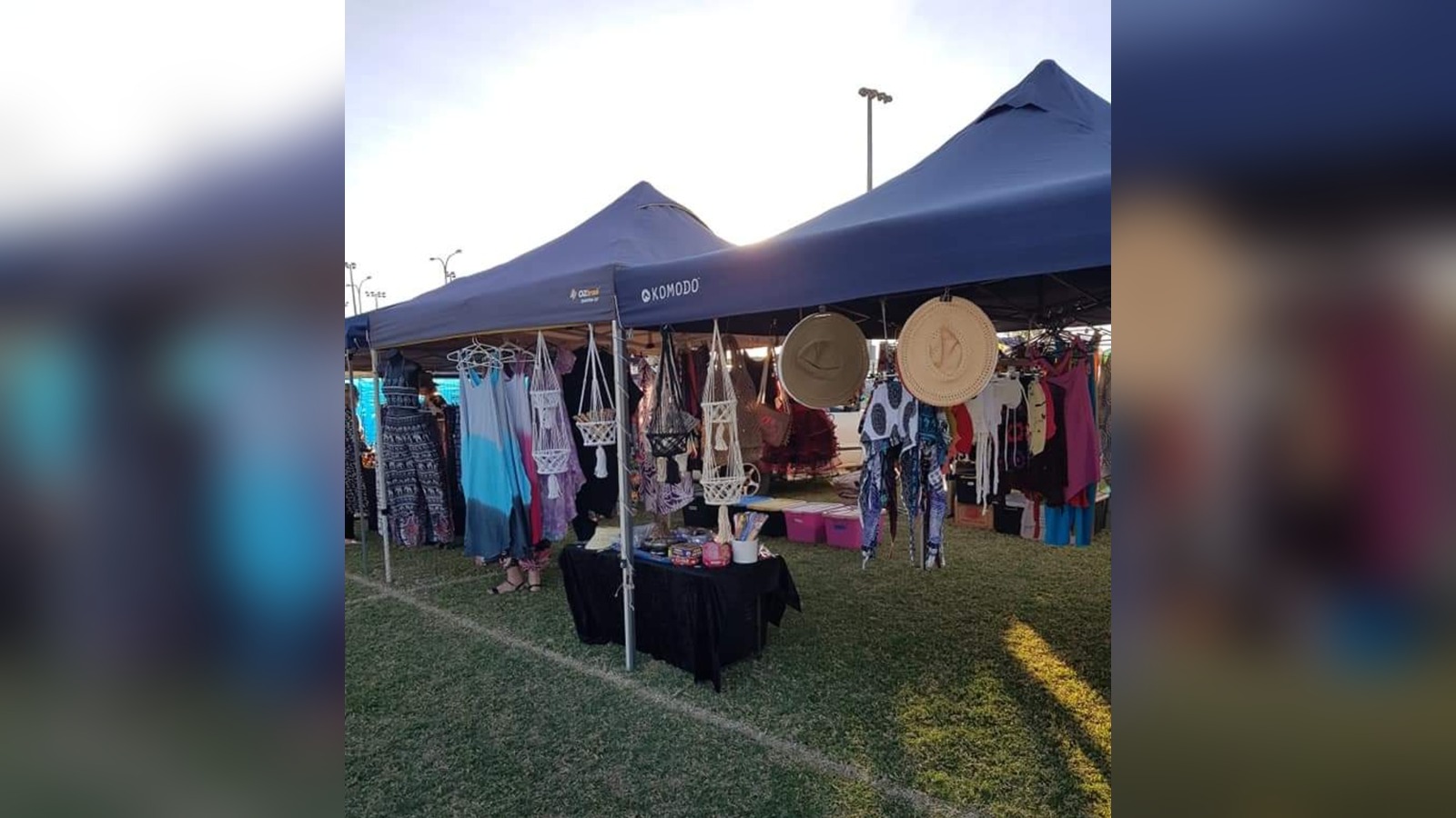 Market stall under a blue marquee displaying patterned dresses